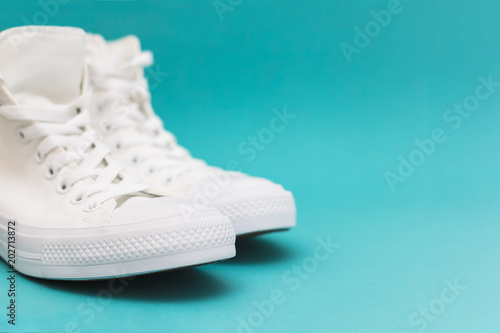 Pair of new white sneakers on blue background