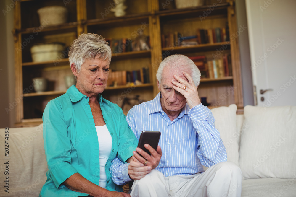 Tense senior couple looking at mobile phone Tense senior couple looking at mobile phone