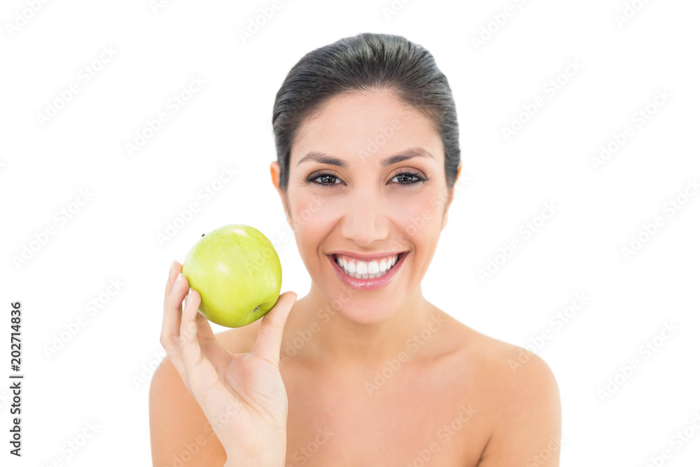 Happy brunette holding a green apple and looking at camera Happy brunette holding a green apple and looking at camera