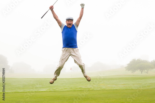 Excited golfer jumping up and smiling at camera 