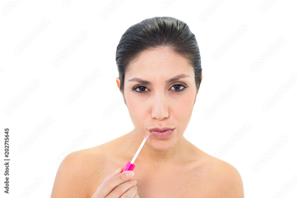 Brunette applying lip gloss and pouting at camera Brunette applying lip gloss and pouting at camera