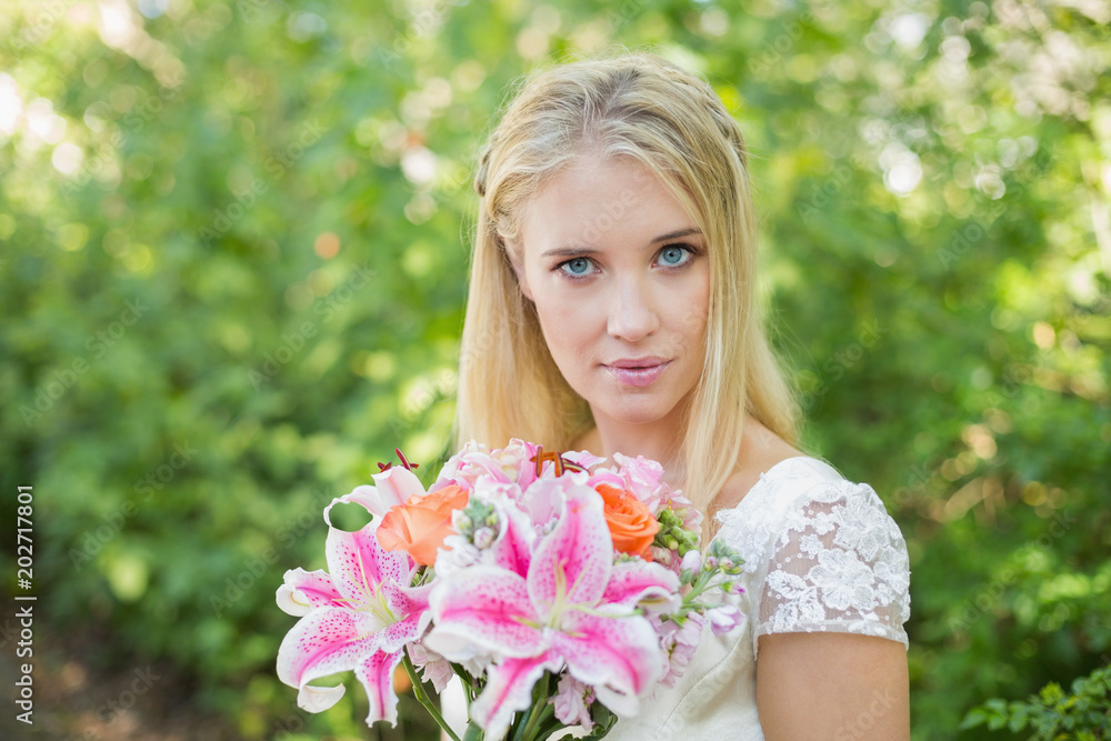 Blonde bride holding colourful bouquet looking at camera Blonde bride holding colourful bouquet looking at camera