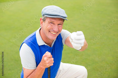 Smiling golfer kneeling on the putting green 