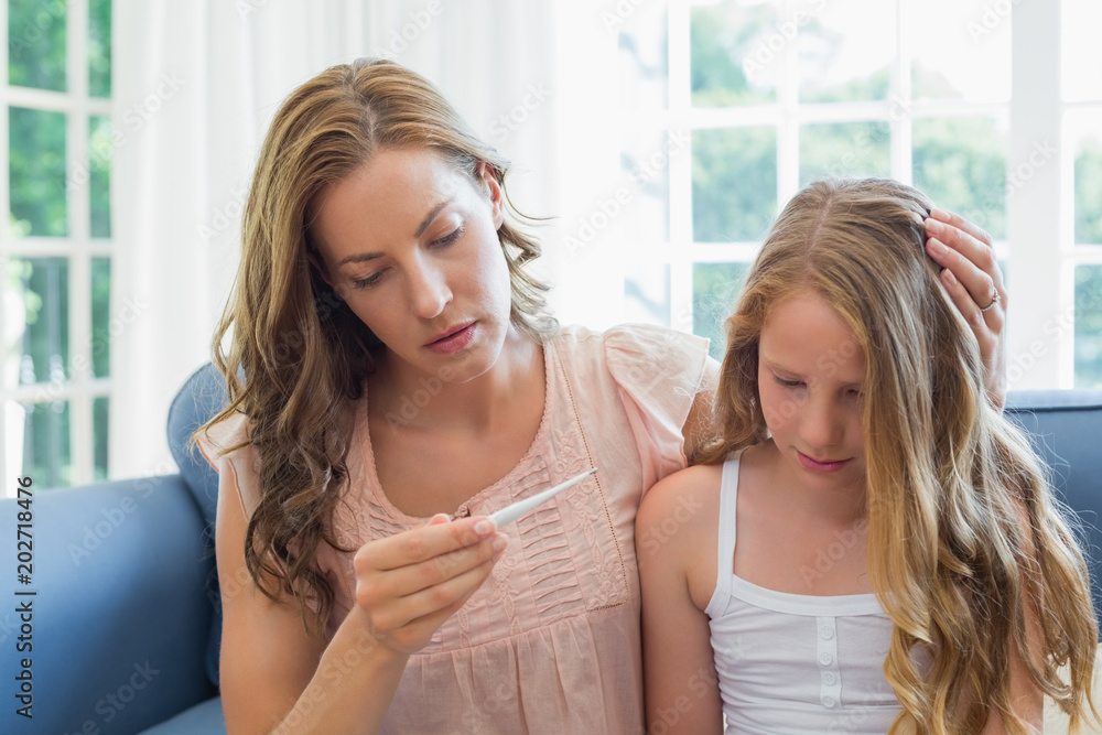 Mother looking at thermometer with sick child Mother looking at thermometer with sick child