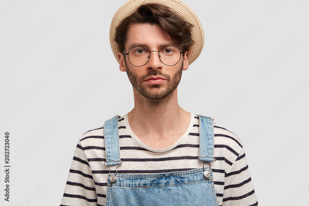 Φωτογραφία Serious bearded young male farmer looks confidently at camera, wears countryside casual clothes, poses against white studio background