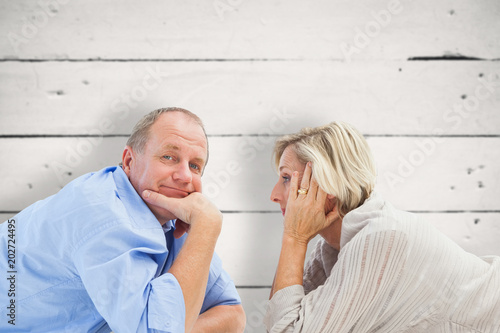 Mature couple lying and smiling against white wood