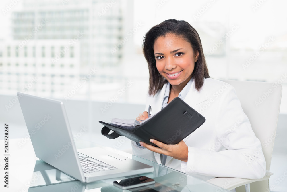 Natural young dark haired businesswoman filling her schedule Natural young dark haired businesswoman filling her schedule