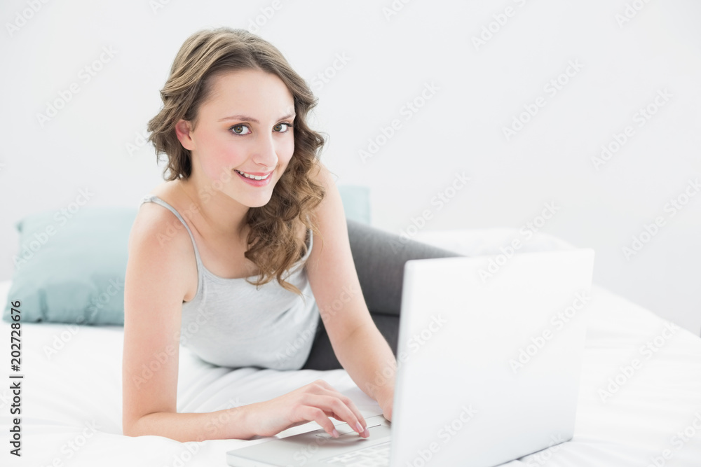 Smiling casual brunette with laptop in bed Smiling casual brunette with laptop in bed