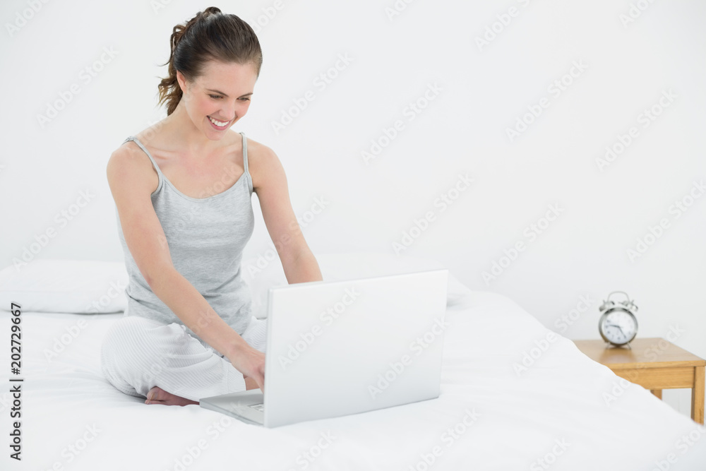Smiling casual woman using laptop in bed Smiling casual woman using laptop in bed