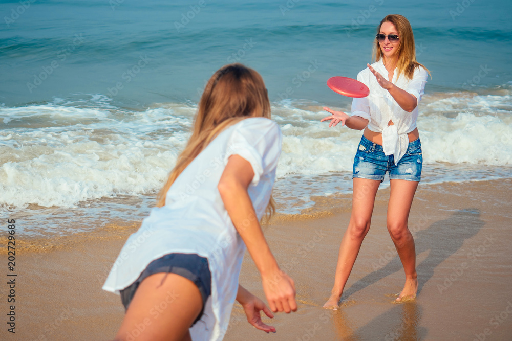 two women on the beach playing with a flying disc two women on the beach playing with a flying disc