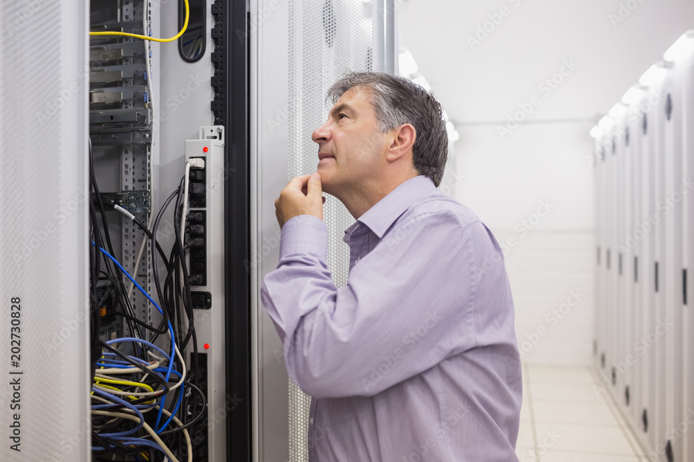 Fototapeta premium Man looking up thoughtfully into server locker