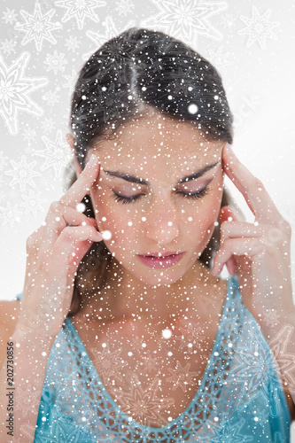 Portrait of a young woman having a headache against snowflakes on silver