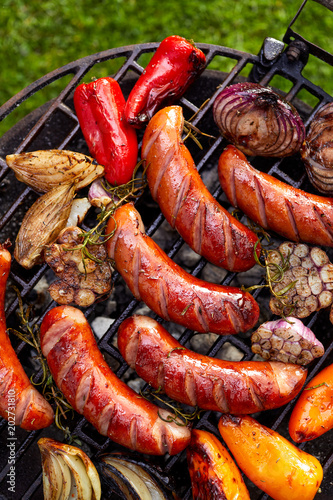 Grilled sausages and vegetables on a grilled plate, outdoor, top view. Grilled food, bbq