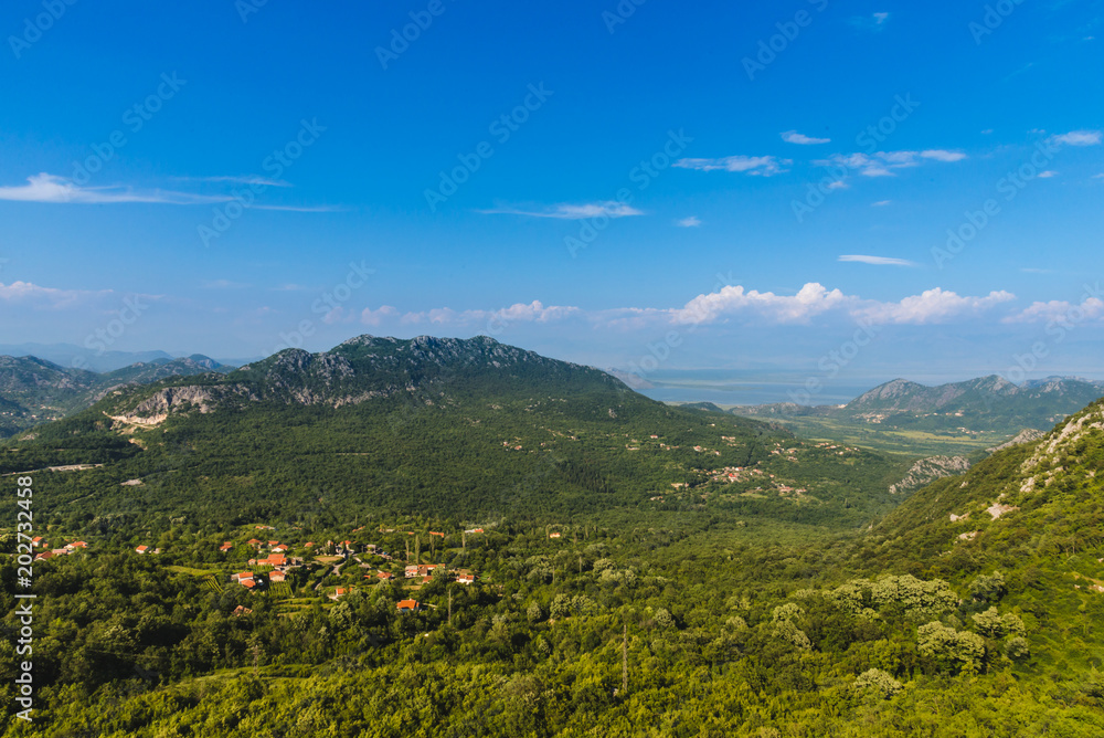 Montenegro landscape with balkan mountain village and rocks by cloudy day. Montenegrin wild nature scenery panoramic view with small town in the mountains valley. Freedom and adventure concept.