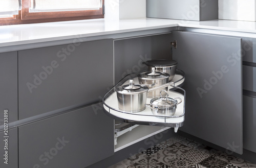 Corner storage mechanism called as magic corner, a perfect solution for pots and pans storage. Easy access for corner kitchen cabinets. Interior in a grey and white colors, grey soft touch matt fronts