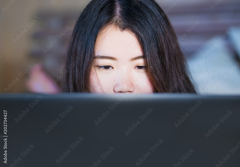 close up portrait of young beautiful 20s Asian Chinese woman lying on bed at night using internet in laptop computer watching on line movie or studying close up portrait of young beautiful 20s Asian Chinese woman lying on bed at night using internet in laptop computer watching on line movie or studying