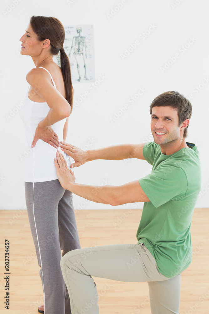 Physiotherapist examining womans back in medical office Physiotherapist examining womans back in medical office