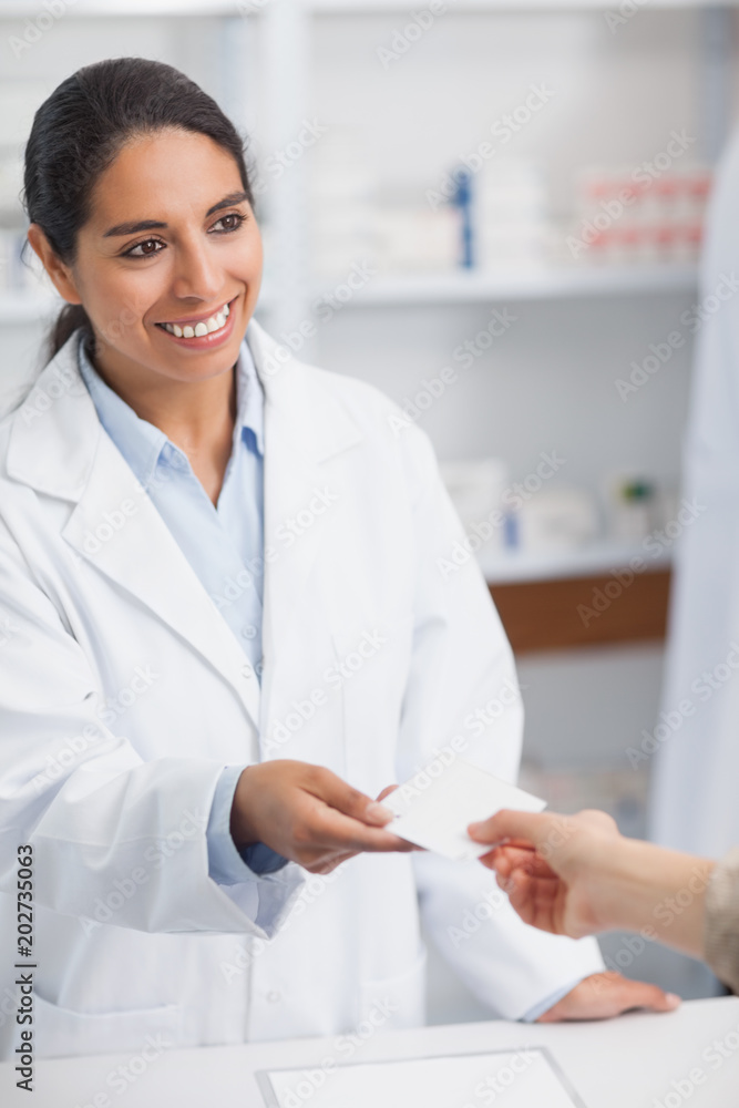 Smiling pharmacist handing paper to a customer Smiling pharmacist handing paper to a customer