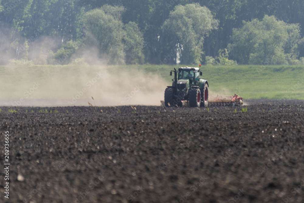 Fototapeta premium Tractor performs spring work in the field