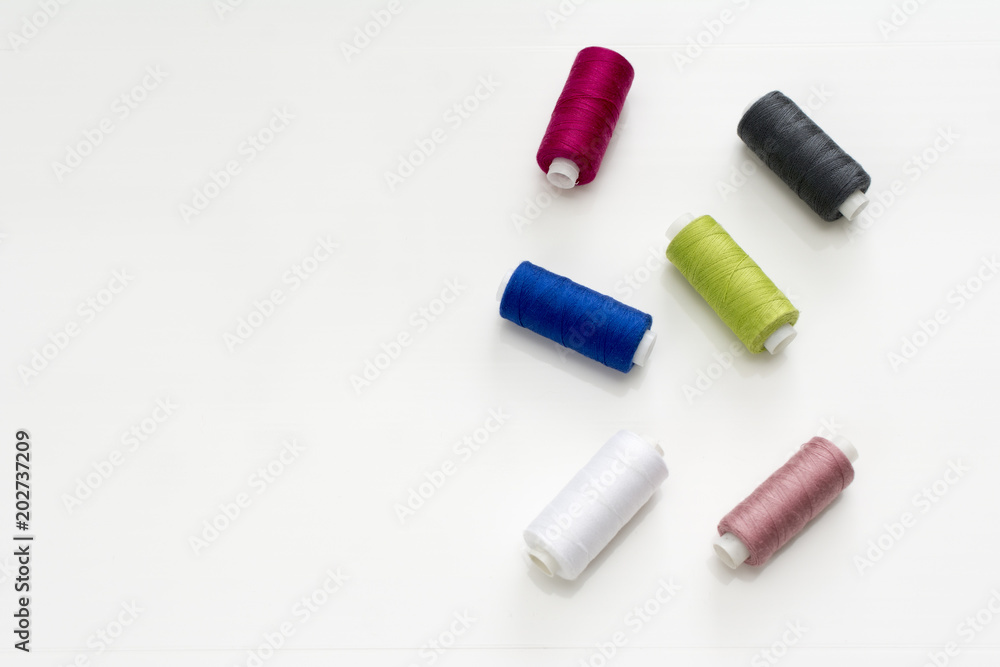 Colored thread coils on white background, sewing, place for text Colored thread coils on white background, sewing, place for text