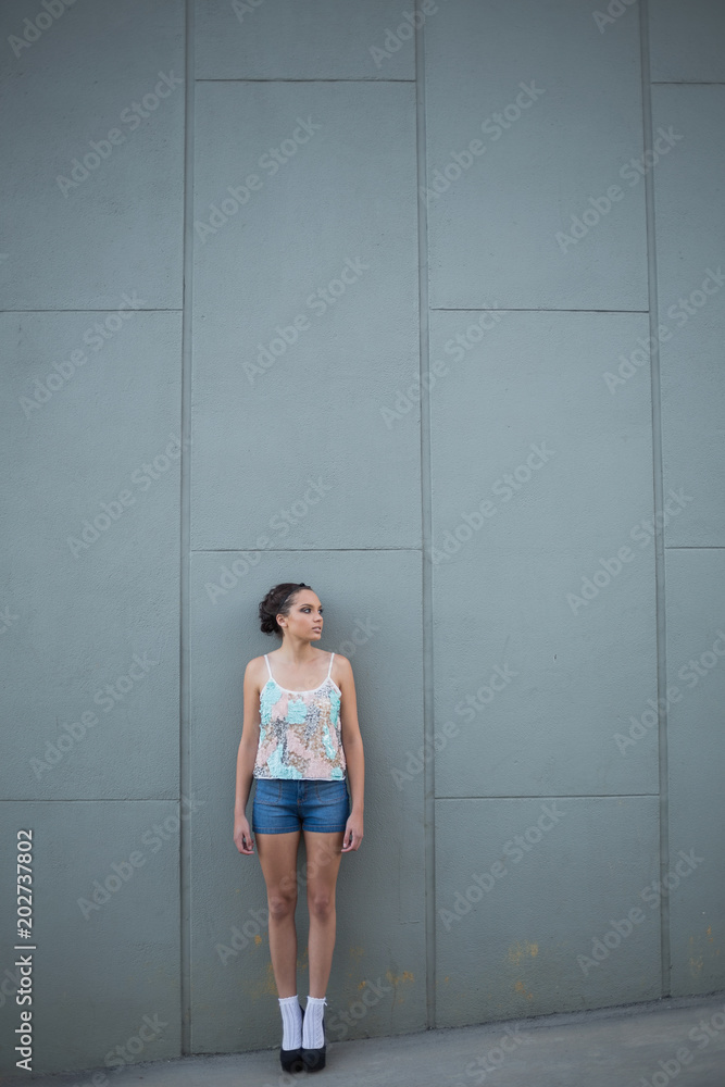 Pretty woman with high heels standing in front of a grey wall