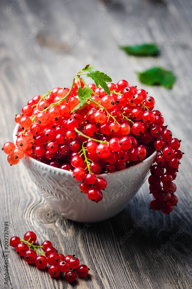 Red currant berries in a bowl on old wooden table. Selective focus, space for text. Red currant berries in a bowl on old wooden table. Selective focus, space for text.