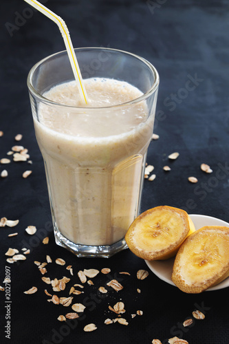 Banana smoothie with oats on dark background
