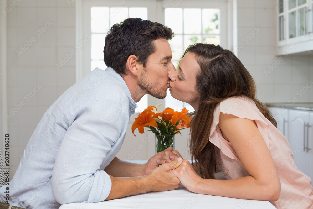 Side view of a loving couple kissing in kitchen Side view of a loving couple kissing in kitchen