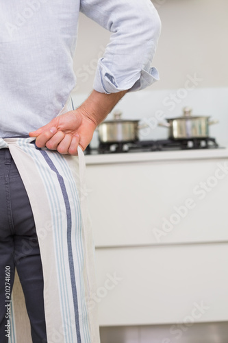 Mid section of a man wearing apron in kitchen