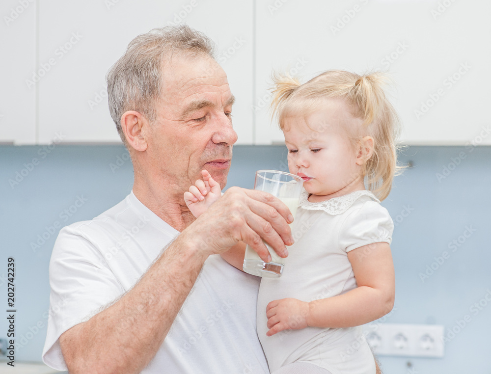 Senior man gives milk to a child Senior man gives milk to a child