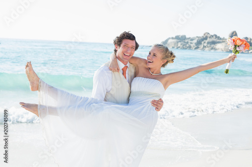 Laughing groom carrying his pretty blonde wife
