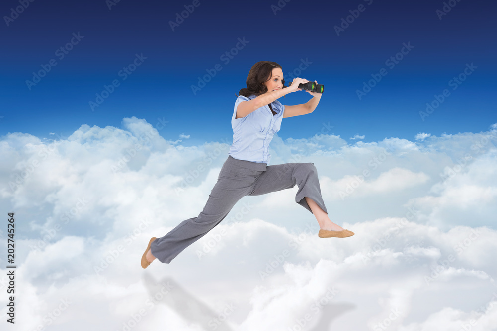 Cheerful classy businesswoman jumping while holding binoculars against bright blue sky over clouds Cheerful classy businesswoman jumping while holding binoculars against bright blue sky over clouds