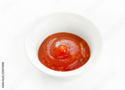 Tomato sauce ketchup swirl in white bowl isolated on white background