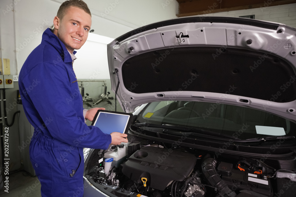 Mechanic looking at camera while holding a tablet computer Mechanic looking at camera while holding a tablet computer