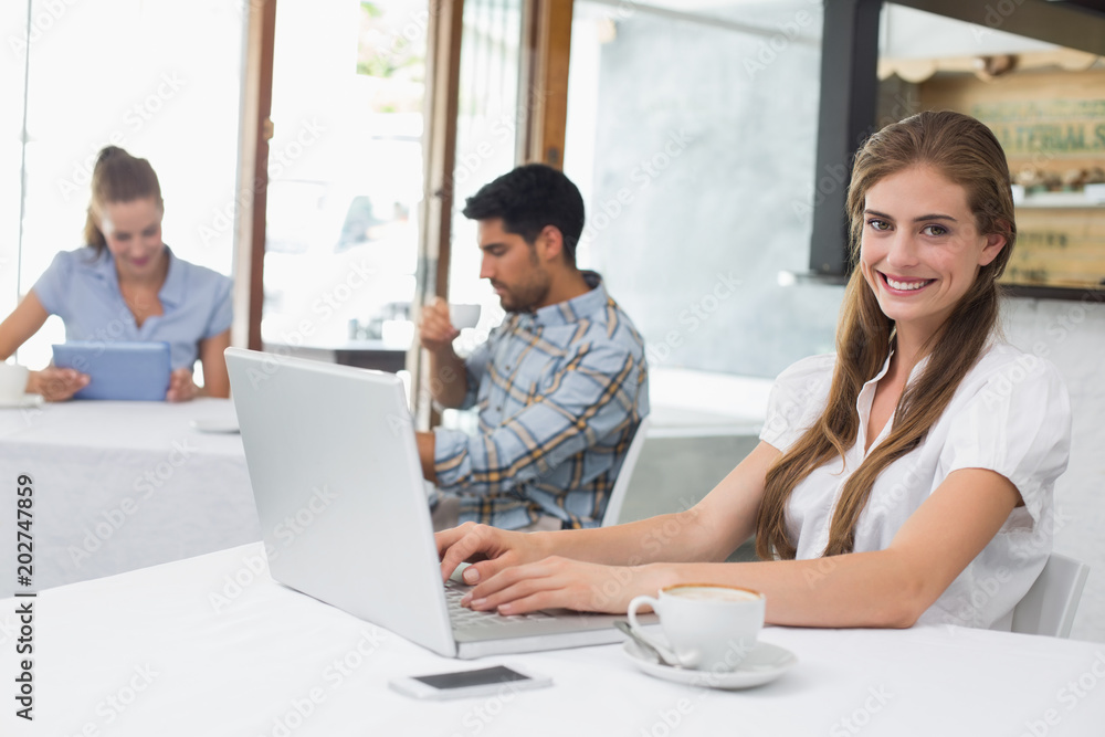 Smiling woman using laptop in coffee shop Smiling woman using laptop in coffee shop