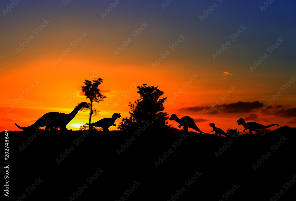 silhouettes of dinosaurs in the forest on sunset background with copy space add text