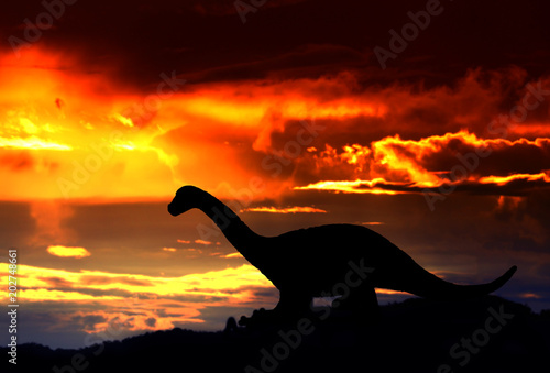 Fototapeta Naklejka Na Ścianę i Meble -  silhouettes of dinosaurs in the forest on sunset background with copy space add text