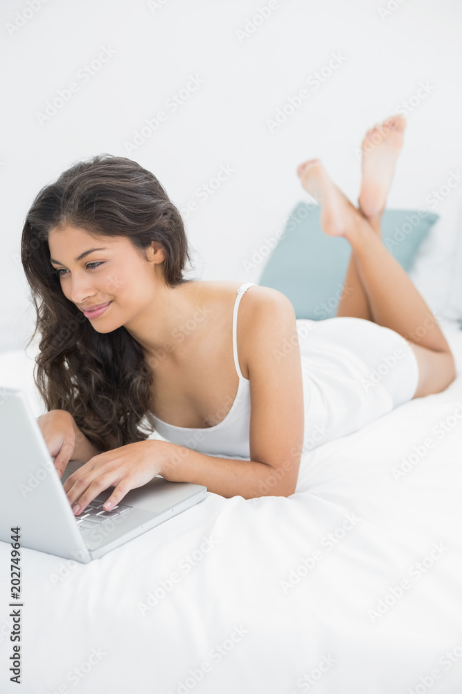 Smiling casual woman using laptop in bed Smiling casual woman using laptop in bed
