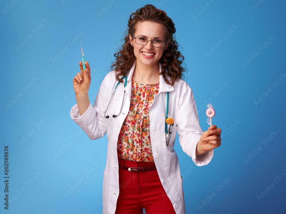 smiling pediatrist doctor with syringe and lollypop on blue smiling pediatrist doctor with syringe and lollypop on blue