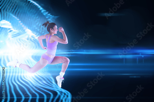 Fit brunette running and jumping against black background with spark