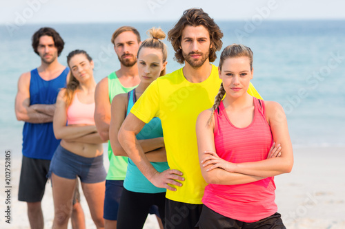 Friends in sports clothing standing at beach