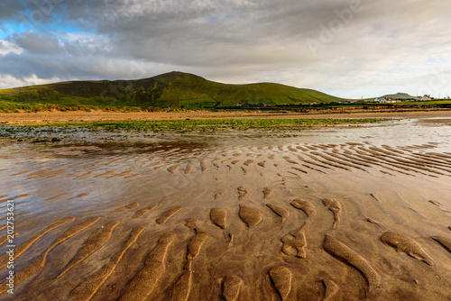 Flooded sandy beach on the foreground and hills in the background