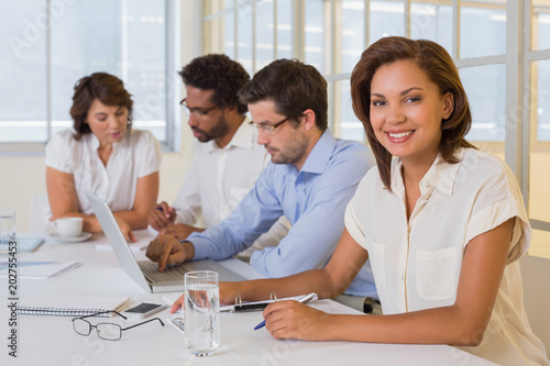 Smiling businesswoman with colleagues in meeting at office
