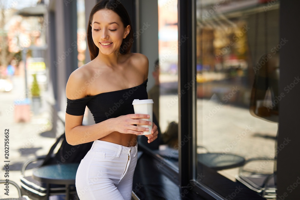 Brunette girl stand on the street look at camera and dring her delicious coffee from white cup, spring time photo shoot Brunette girl stand on the street look at camera and dring her delicious coffee from white cup, spring time photo shoot