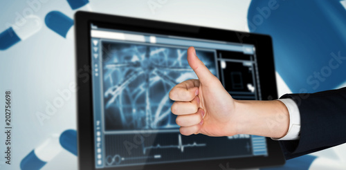 Hand showing thumbs up against cells on a digital tablet