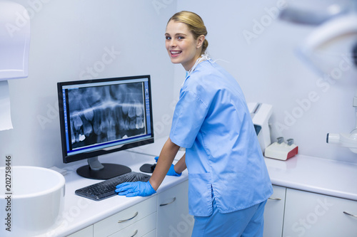 Portrait of female nurse examining x-ray report on computer photo