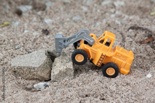 Plastic toy orange color for construction.by Impact Drill activity of Drilling large boulders on soil ground..