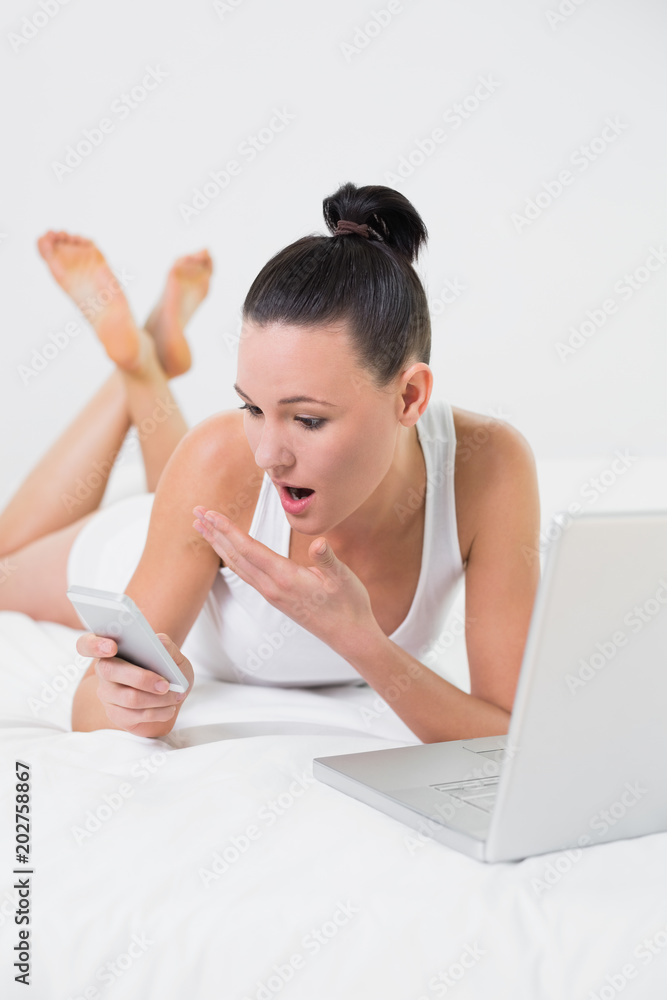 Shocked casual woman with cellphone and laptop Shocked casual woman with cellphone and laptop