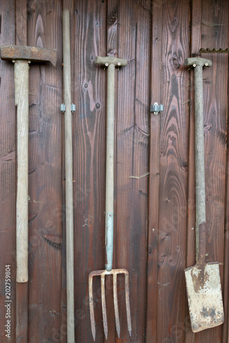 Gartenarbeitsgeräte aufgehängt an einem Holzschuppen
