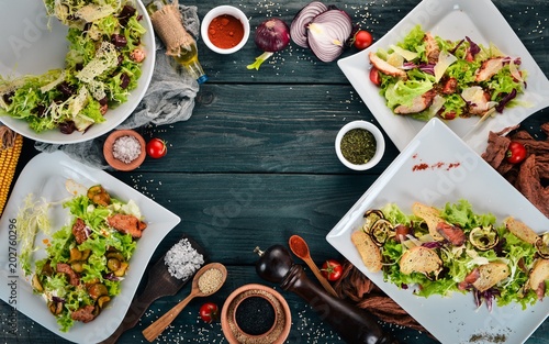 A set of salads. Lettuce, salmon, veal. Top view. On a wooden background. Copy space. © Yaruniv-Studio